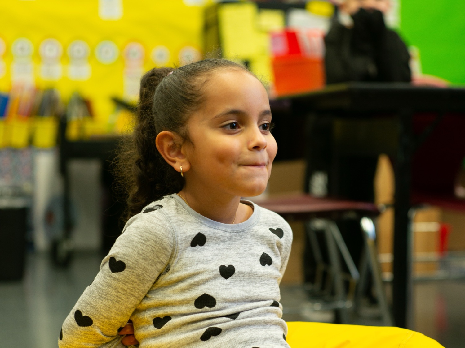 A child smiling on a yellow beanbag in a program room
