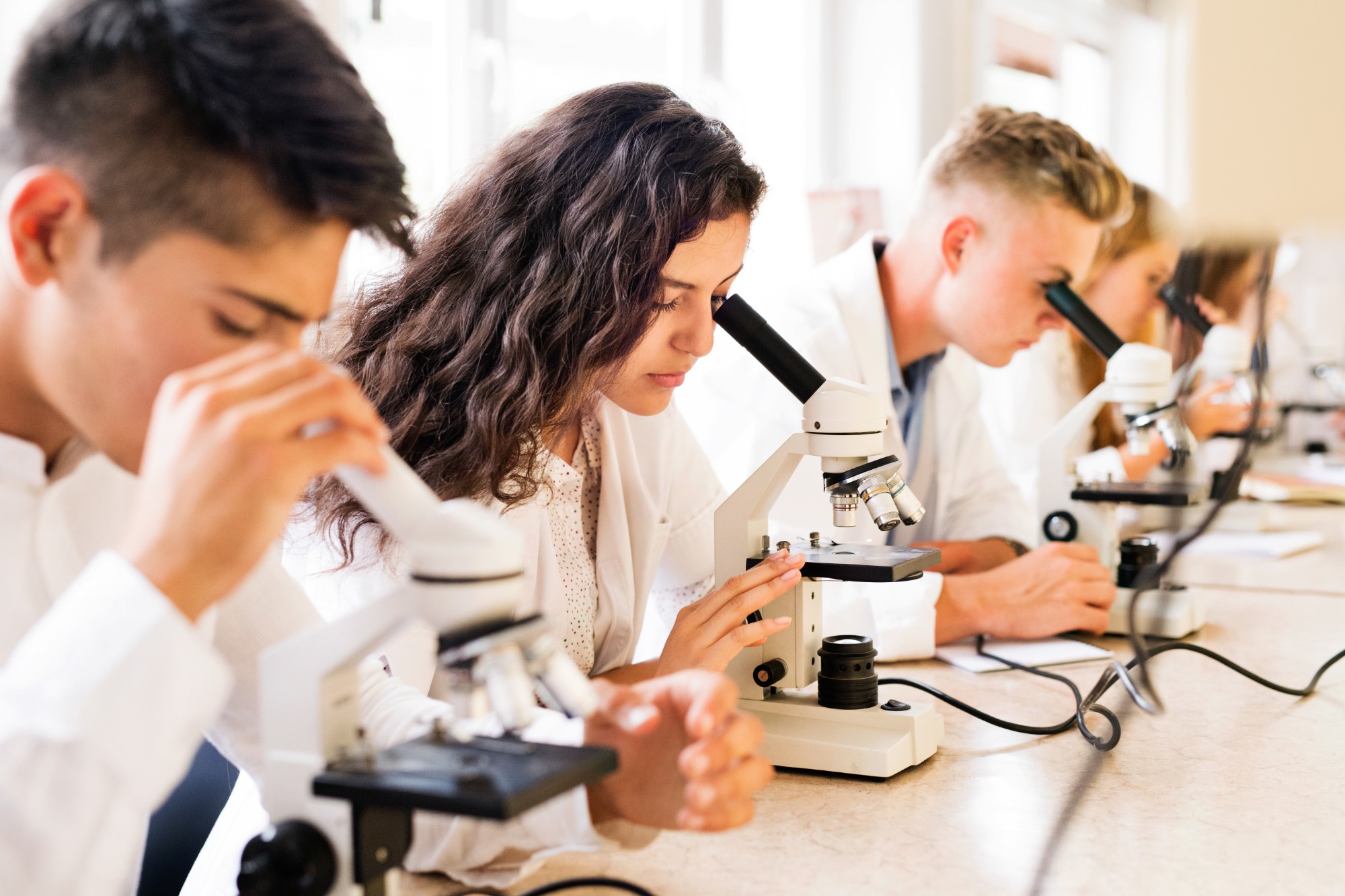 High school students using microscopes in a science lab
